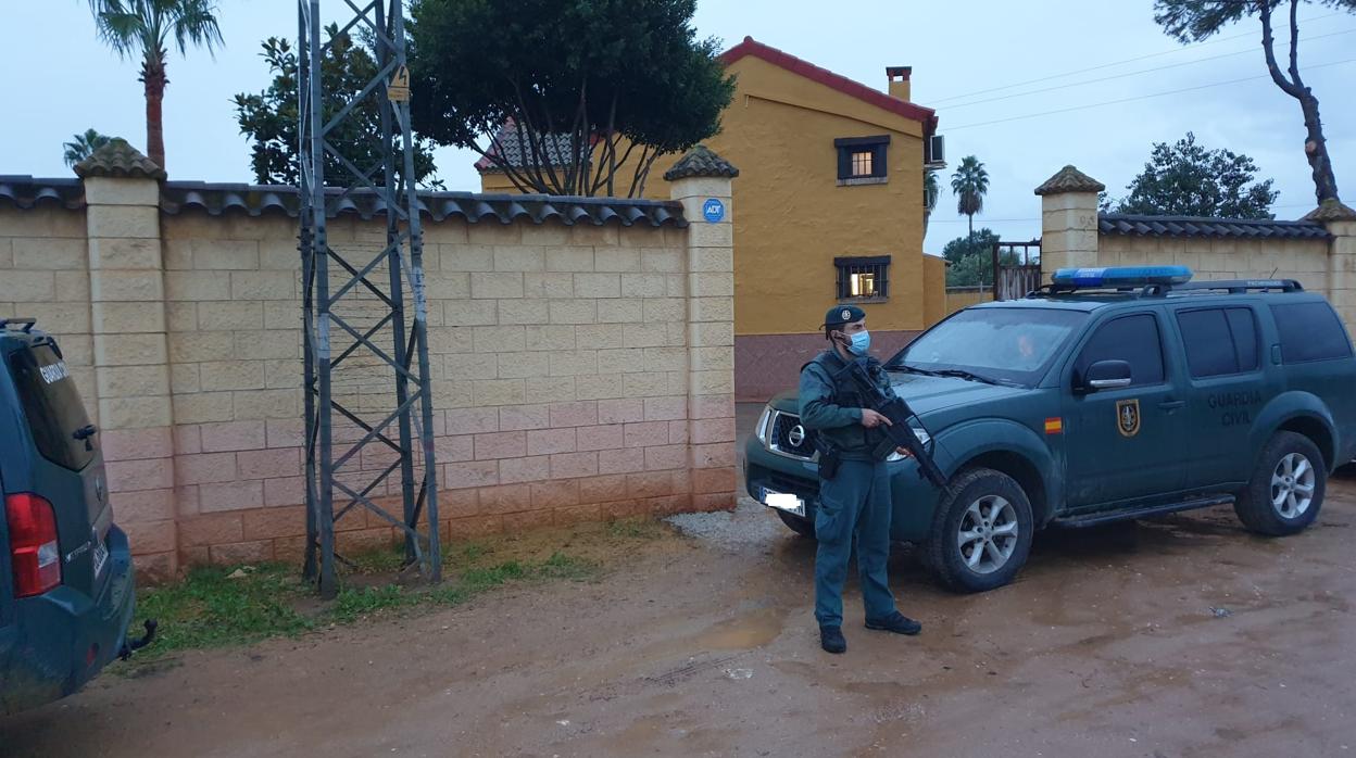 Un agente de la Guardia Civil custodia una de las viviendas registradas en Sevilla