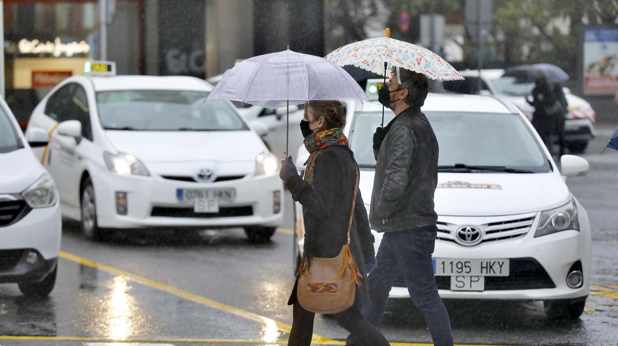 Dos personas se resguardan de la lluvia, este viernes en Sevilla