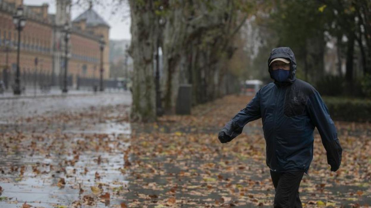 Una persona camina con chubasquero por Sevilla