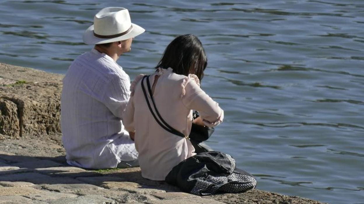 Una pareja descansa junto al río en Sevilla