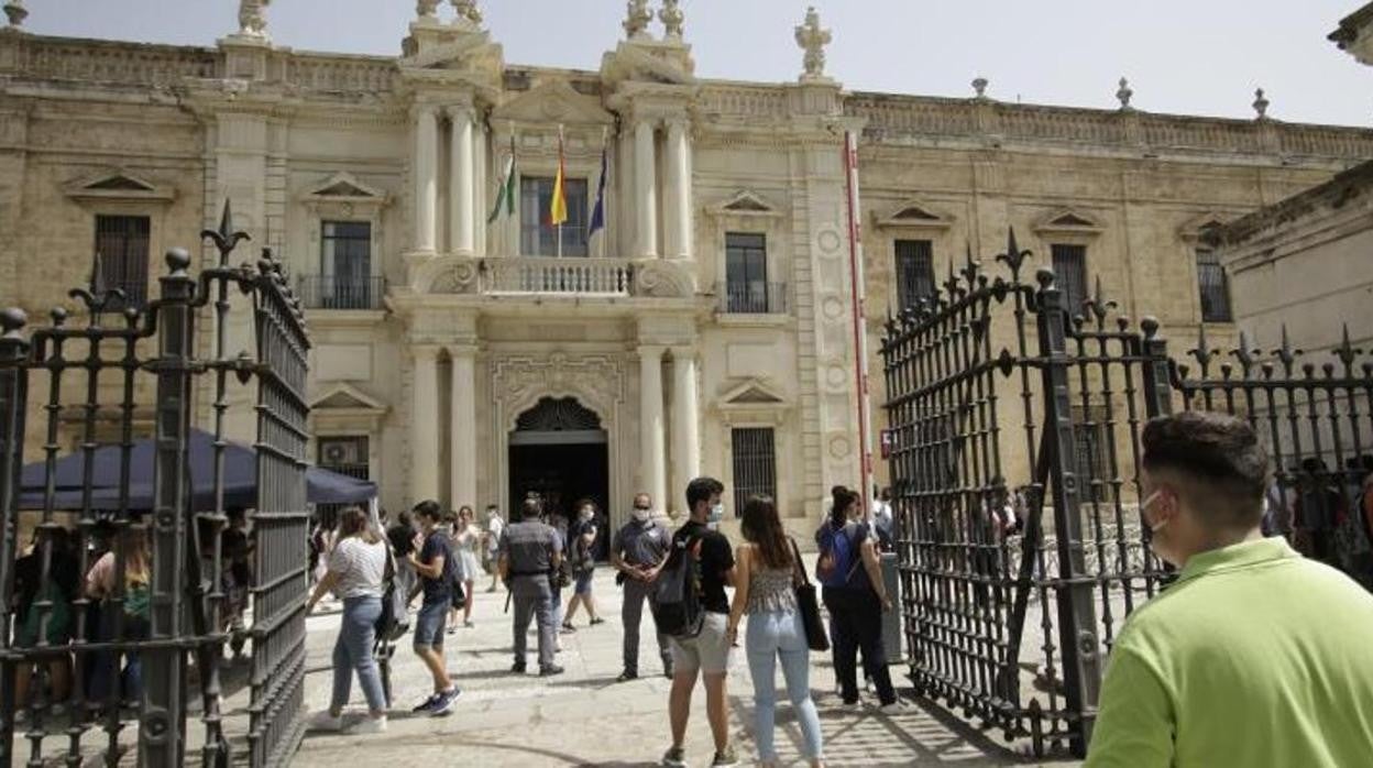 Fachada de la Universidad de Sevilla, con varios alumnos entrando con mascarillas