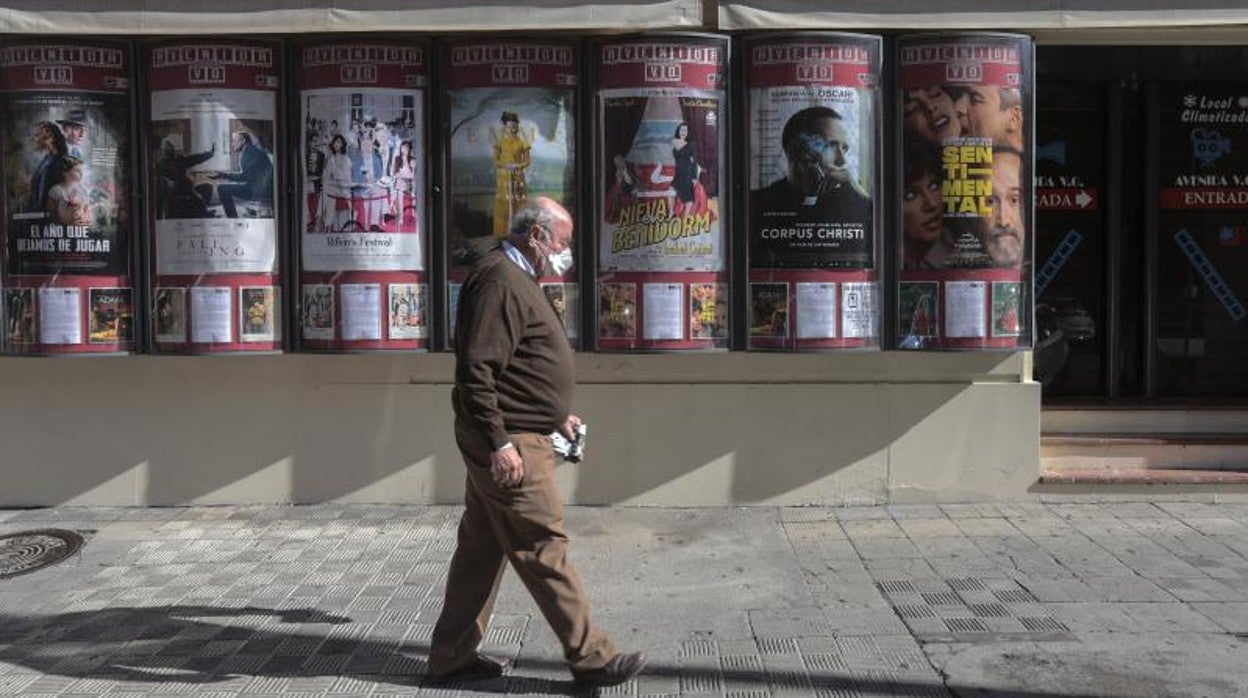 Un ciudadano pasa ante la cartelera de uno de los cines cerrados