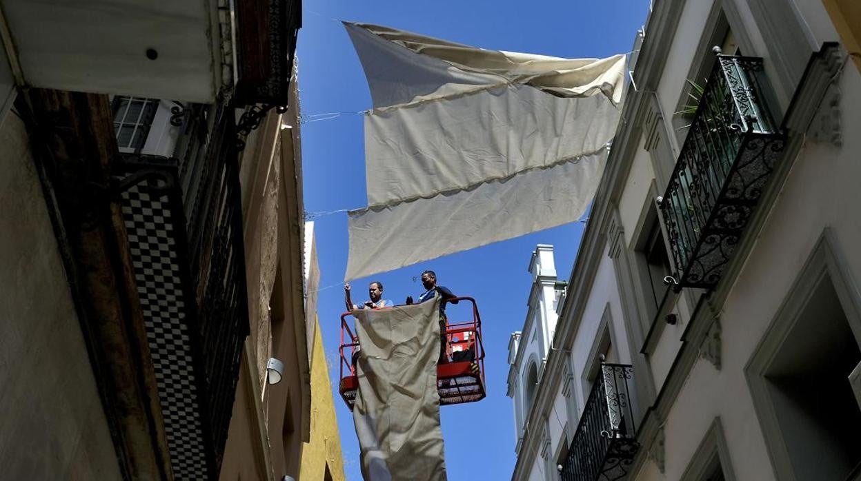 Operarios instalando los toldos en las calles del Centro de Sevilla