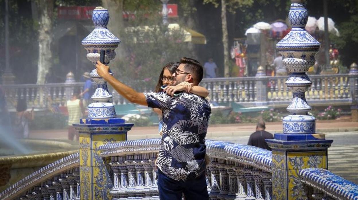 Una pareja se fotografía este verano en la Plaza de España de Sevilla