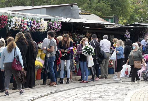 Visitantes adquiriendo flores antes de acceder al cementerio