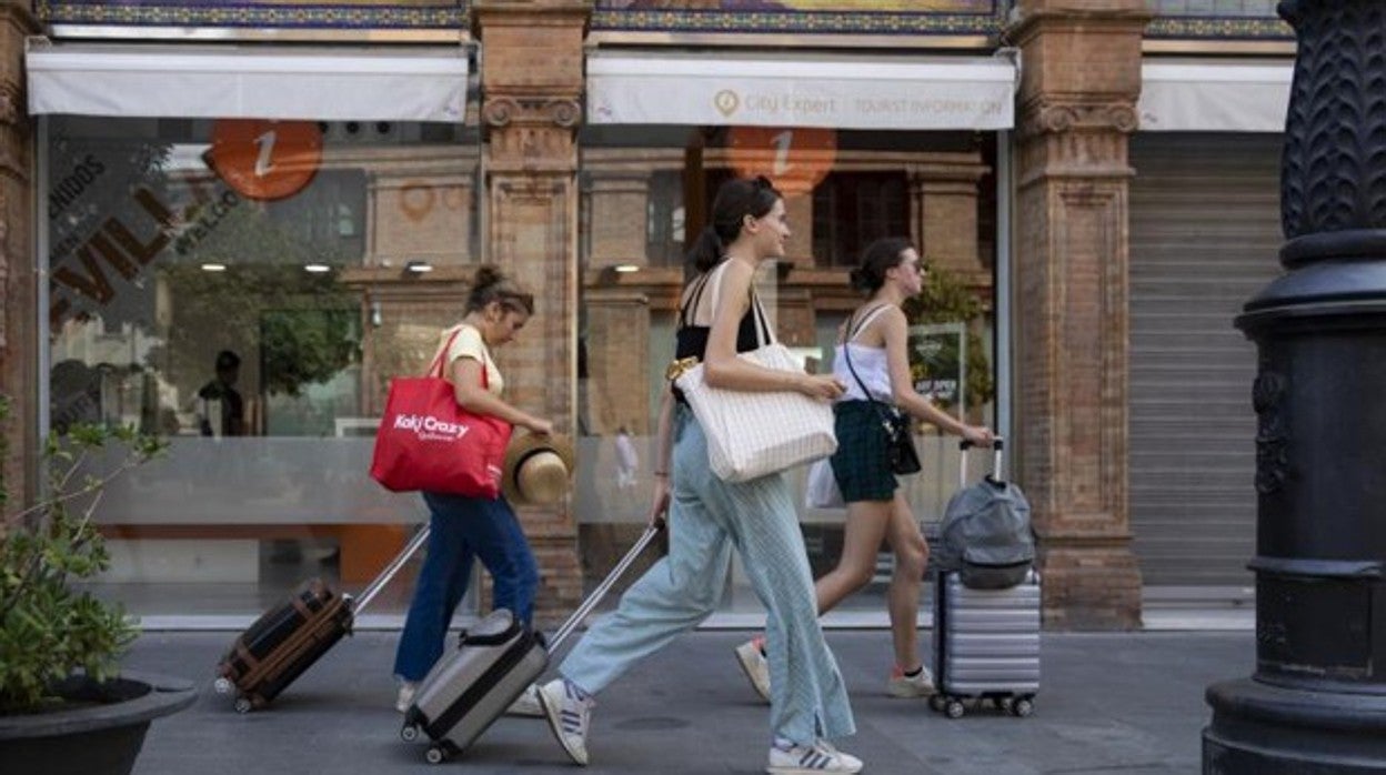 Turistas por las calles de Sevilla tirando de sus maletas