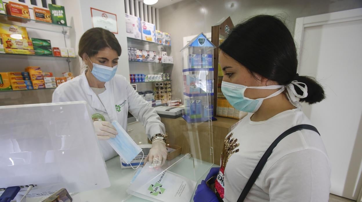 Una mujer comprando mascarillas en una farmacia