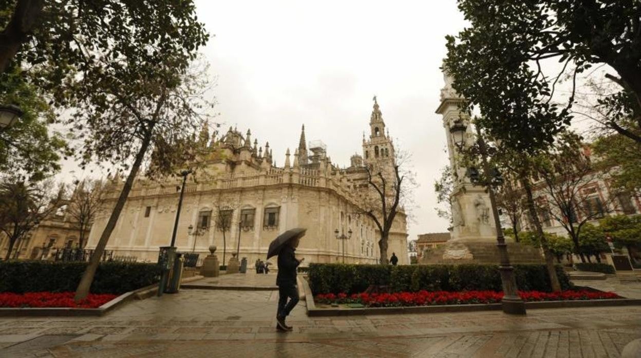 Una oersona se protege de la lluvia con un paraguas mientras pasea por Sevilla