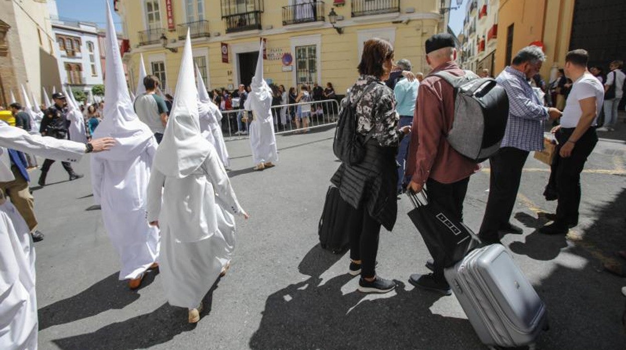 Varios turistas junto a nazarenos en la Semana Santa de 2019