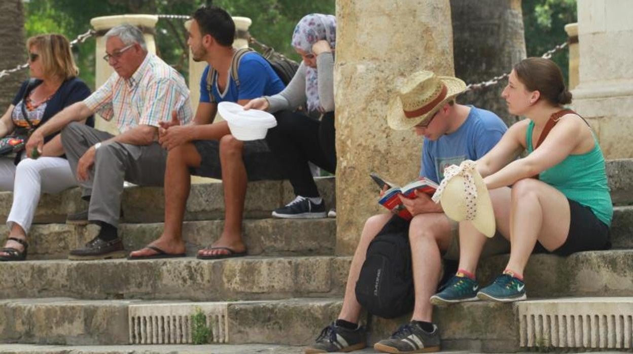 Turistas y visitantes descansan en las escaleras junto a la Plaza del Triunfo