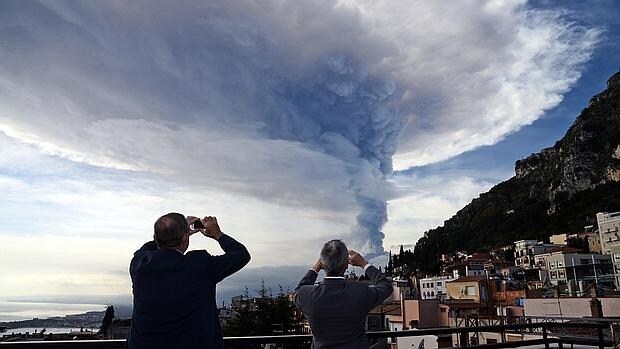 eople take pictures of the smoke rising over the city of Taormina during an eruption of the Mount Etna, one of the most active volcanoes in the world, near Catania, on December 4, 2015. /