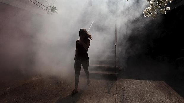 Una mujer sale de su apartamento mientras fumigan el vecindario de Altos del Cerro , en Soyapango, El Salvador, para frenar la propagación del zika