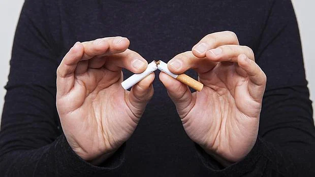 Un ex fumador hace un gesto de no al tabaco, rompiendo unos cigarrillos