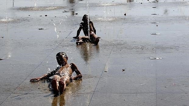 Unos niños se refrescan en una fuente durante la ola de calor