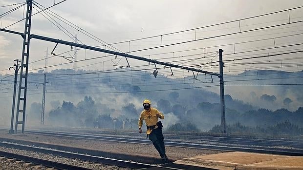 Un bombero en labores de extinción del incendio forestal declarado cerca de la estación de tren de Llançà (Girona) que obligó ayer domingo 1 de mayo a interrumpir el tráfico ferroviario en un tramo de la R11 de Rodalies