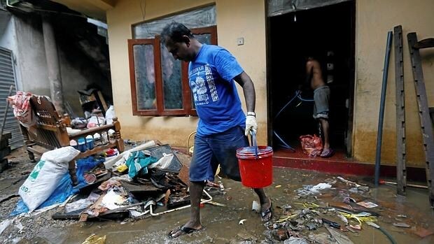 Un hombre limpia su casa, afectada por las inundaciones