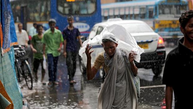 Una mujer intenta resguardarse de las fuertes lluvias en una calle de Calcuta (India)