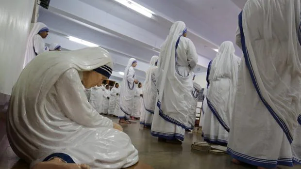 Varias monjas rezan cerca de una estatua de la Madre Teresa