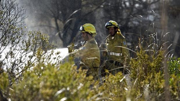 Efectivos del cuerpo de Bomberos durante las labores de extinción del incendio forestal en la zona de Coves Noves, en Arenal d'en Castell, en el norte de Menorca, que ha obligado a desalojar a cerca de 600 personas que viven en estos núcleos residenciales del municipio de Es Mercadal