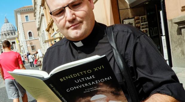 Un párroco lee las memorias del Papa emérito Benedicto XVI, hoy en la avenida próxima al Vaticano 