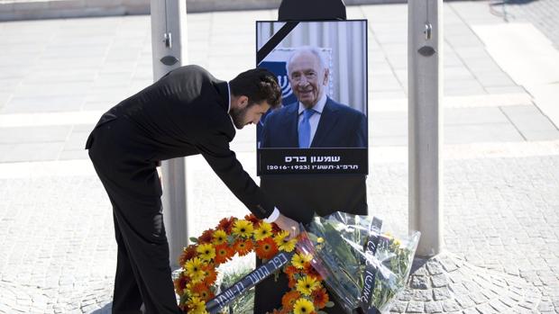 Un israelí coloca flores ante un retrato del expresidente israelí Simon Peres durante un acto público celebrado en el Parlamento o Kneset, en Jerusalén