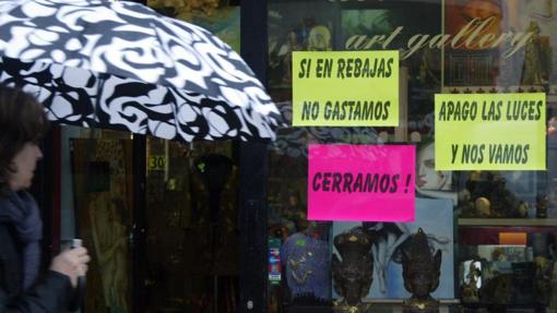 Un mujer pasa junto a un escaparate del centro deBilbao con curiosos y contundentes mensajes animando al consumo