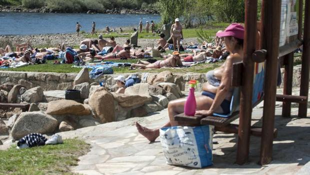 Varias personas disfrutan del buen tiempo en la zona fluvial del río Miño y las termas de A Chavasqueira el pasado sábado, cuando se rozaron los 30ºC