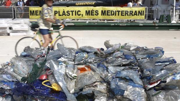 Un ciclista observa un montón de bolsas de plástico, momentos antes de la presentación del informe «Un Mediterráneo lleno de plástico»