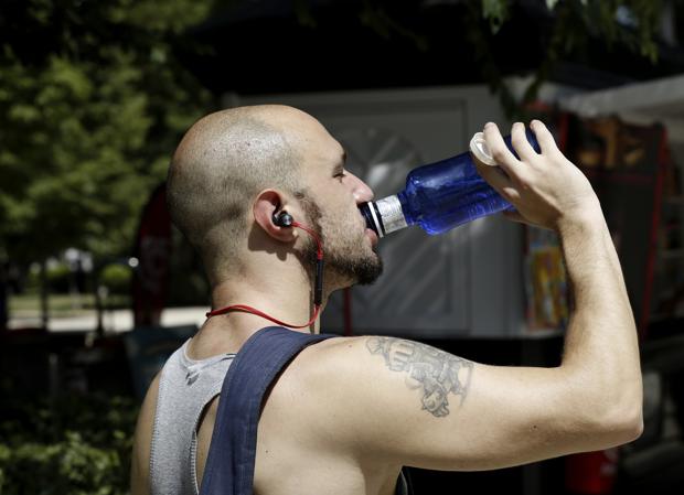 Un hombre bebe en el parque del Retiro de Madrid para hacer frente a las altas temperaturas