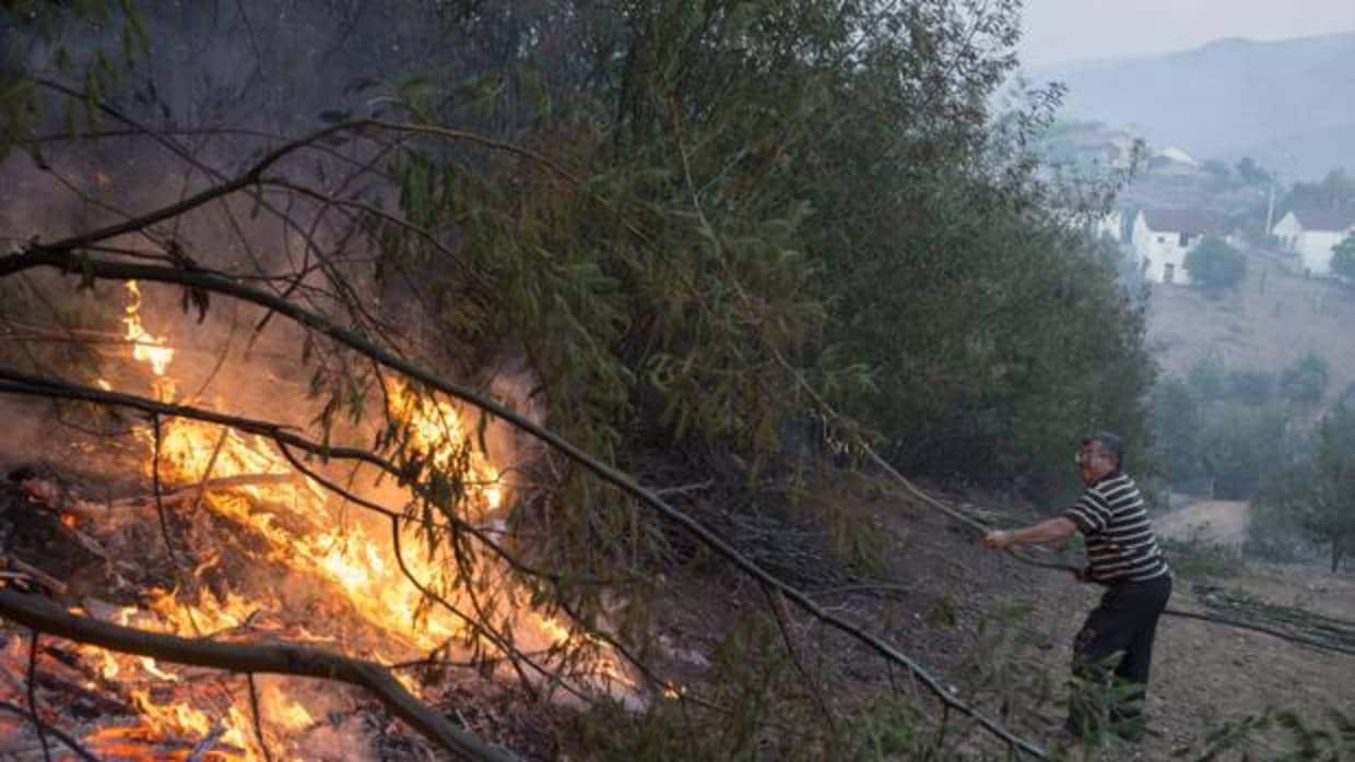Un vecino del pueblo de Queirugás, en Ourense, trata de apagar las llamas del incendio forestal