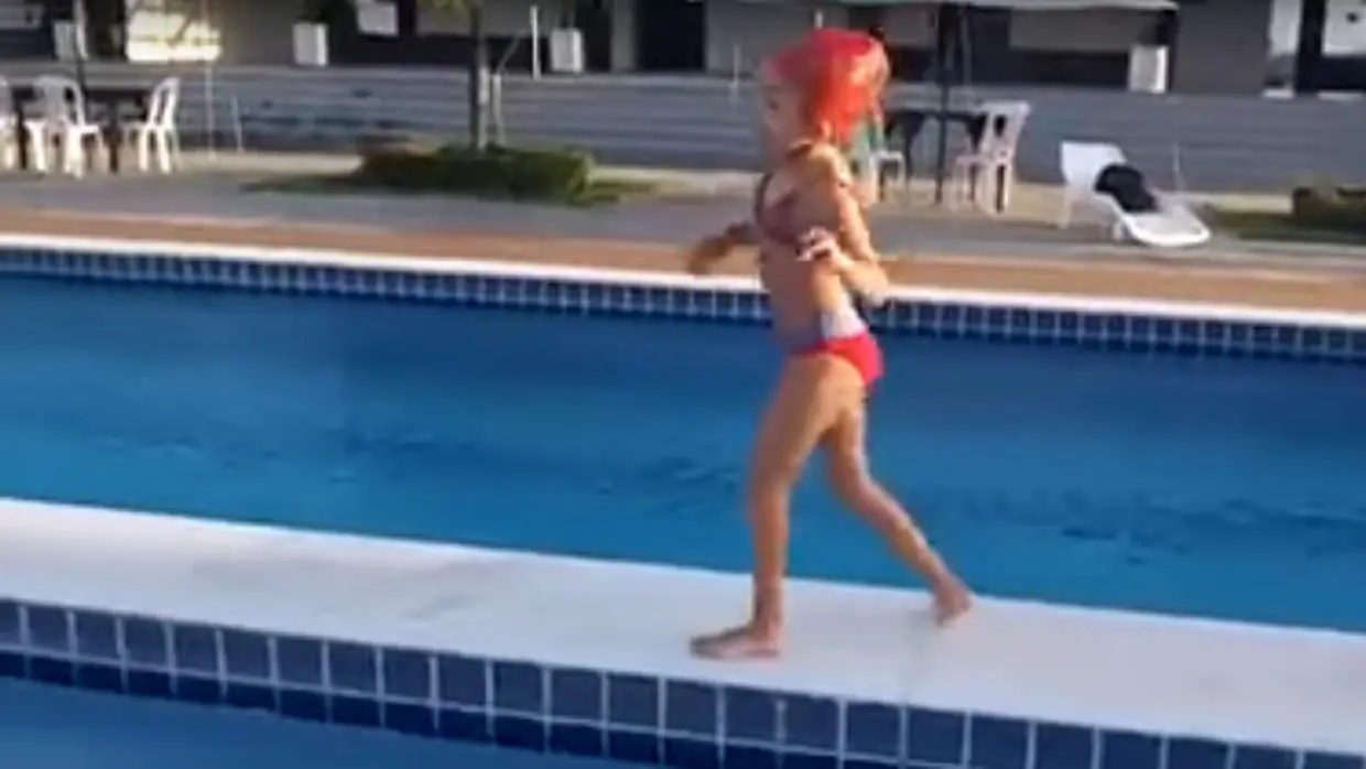 La niña con parálisis, caminando por la pasarela de una piscina