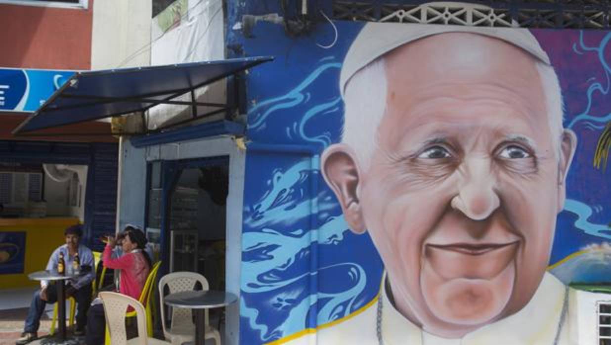 Residentes comparten en un local junto a un mural con la imagen del Papa Francisco en Villavicencio (Colombia)