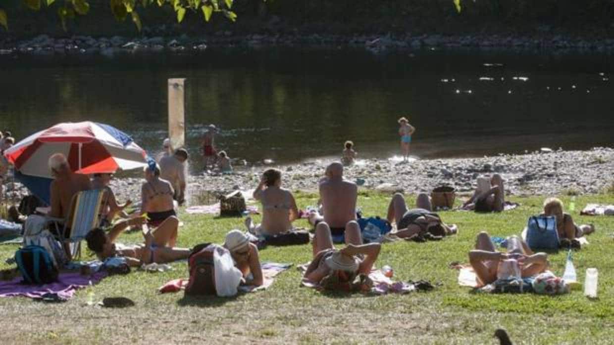 Varias personas disfrutan este martes en el río Miño y las termas de A Chavasqueira, de las agradables temperaturas registradas en la región