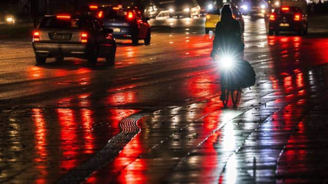 Una mujer monta una bicicleta en una calle mojada durante una noche lluviosa de otoño hoy