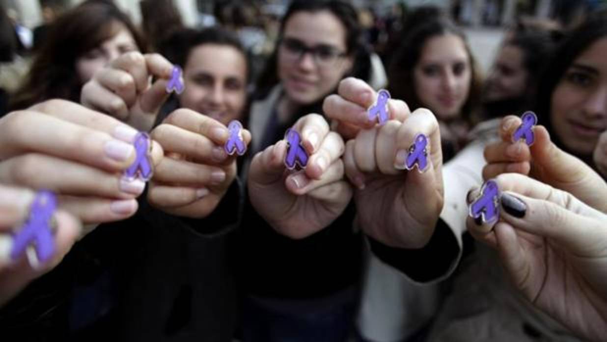 Varias jóvenes muestran lazos de color violeta, que simbolizan la lucha contra la violencia machista