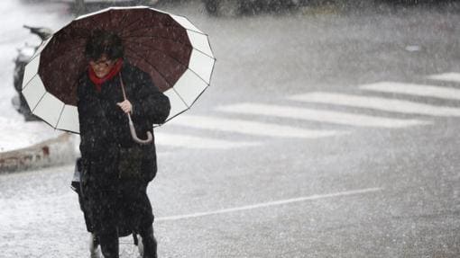 Una mujer se protege de la lluvia durante una tormenta en Marbella (Málaga) donde se acumularon 150 mm