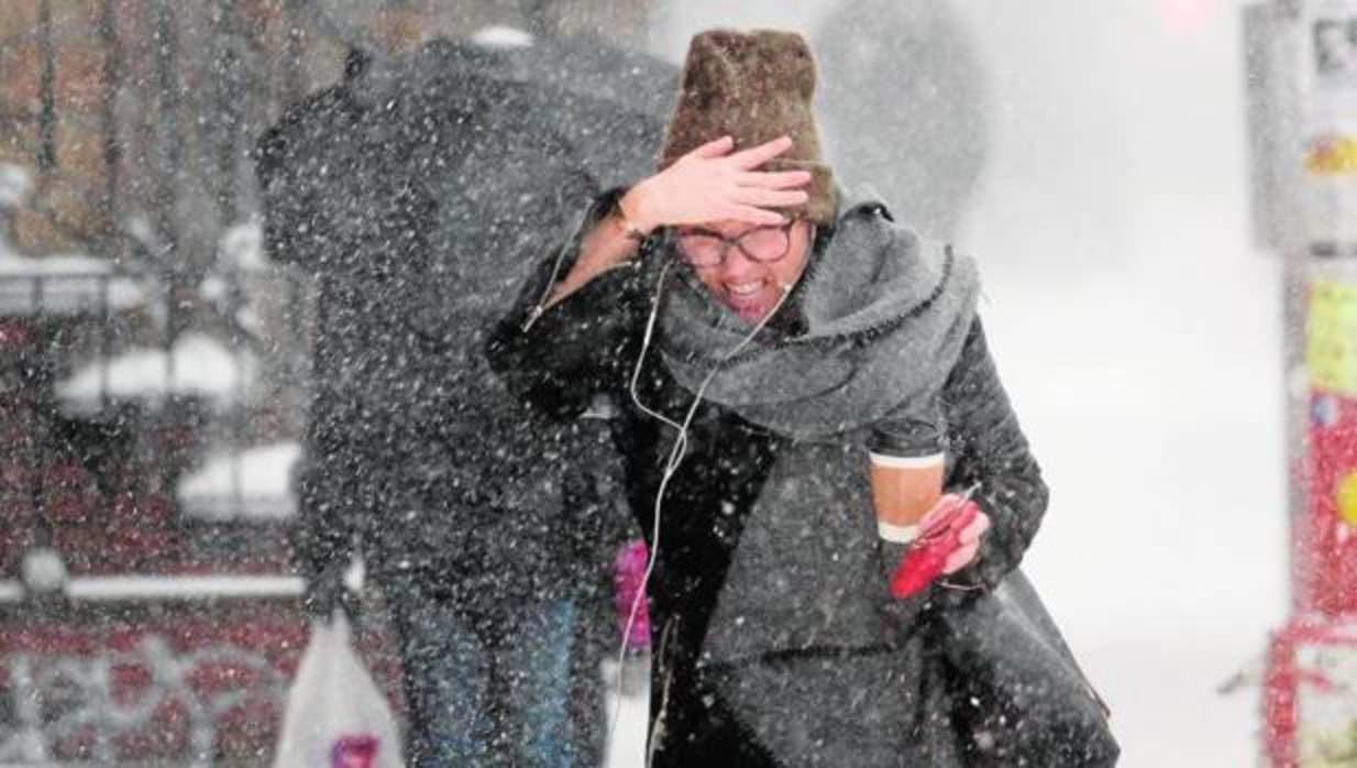 Una mujer se cubre la cara para protegerse durante una tormenta de viento y nieve en Brooklyn (Estados Unidos)