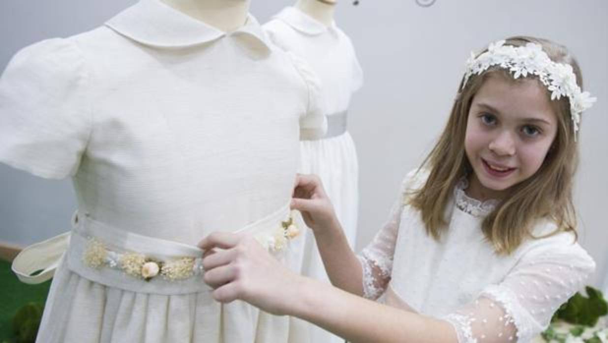 Una niña se prueba el vestido de su Comunión en la tienda de Cáritas en la calle Orense de Madrid