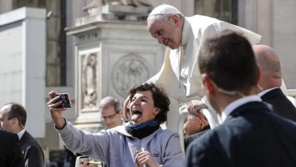 El Papa Francisco posa para un selfie con un joven a su llegada a la audiencia general de los miércoles en la plaza de San Pedro del Vaticano