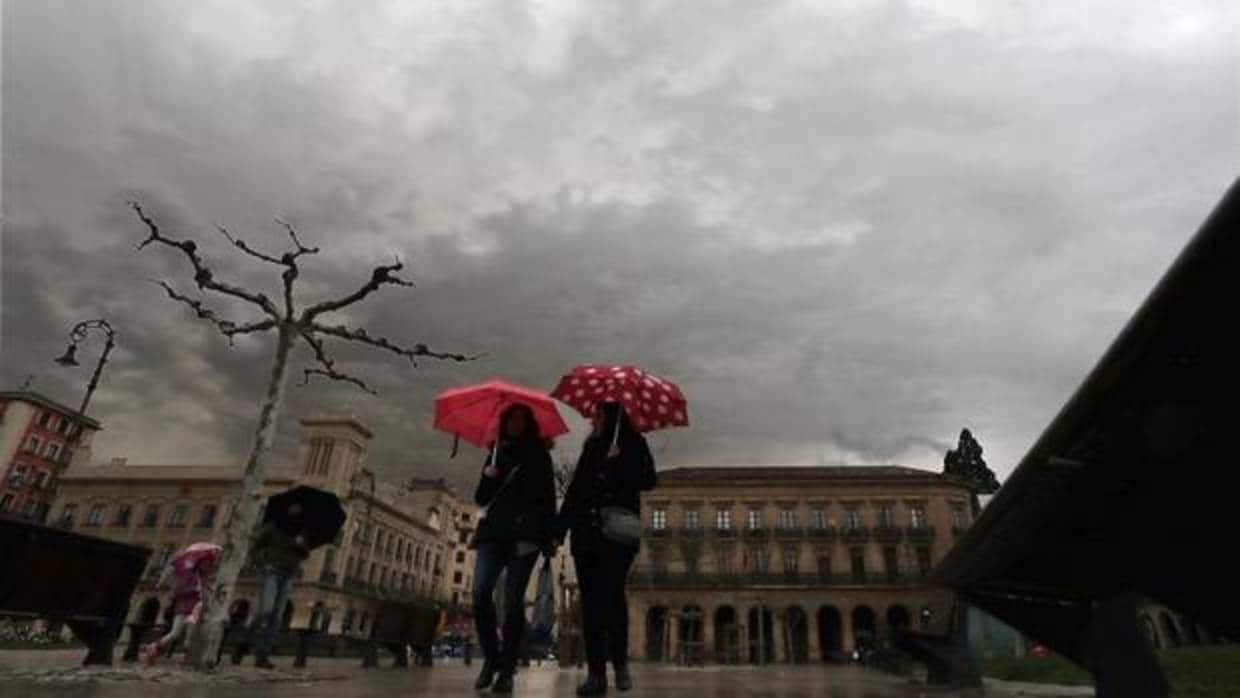 Dos personas se protegen del agua con un paraguas este domingo en al Plaza del Castillo de Pamplona