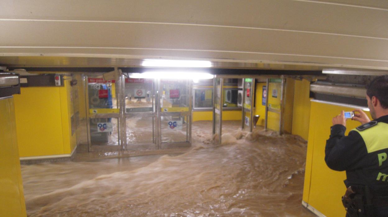 Un policía local fotografía los efectos de la tromba de agua que inundó la estación de Ciudad Lineal