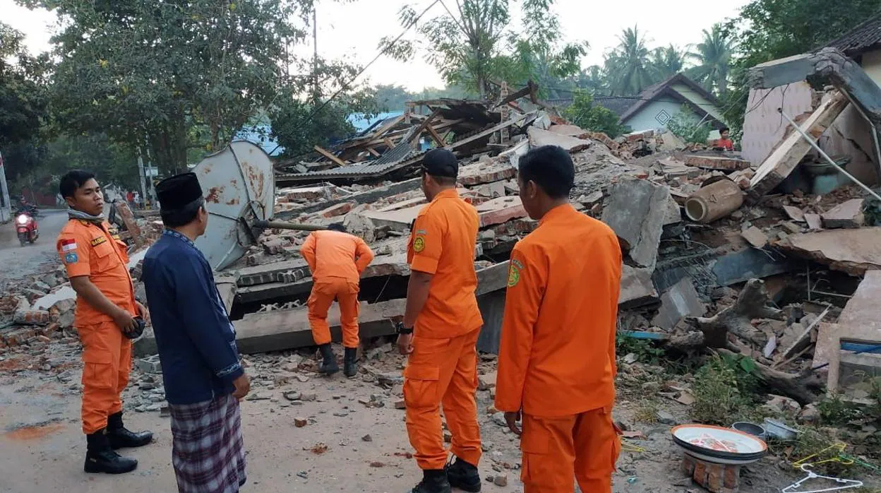 Miembros de los cuerpos de rescate revisan las ruinas de una casa