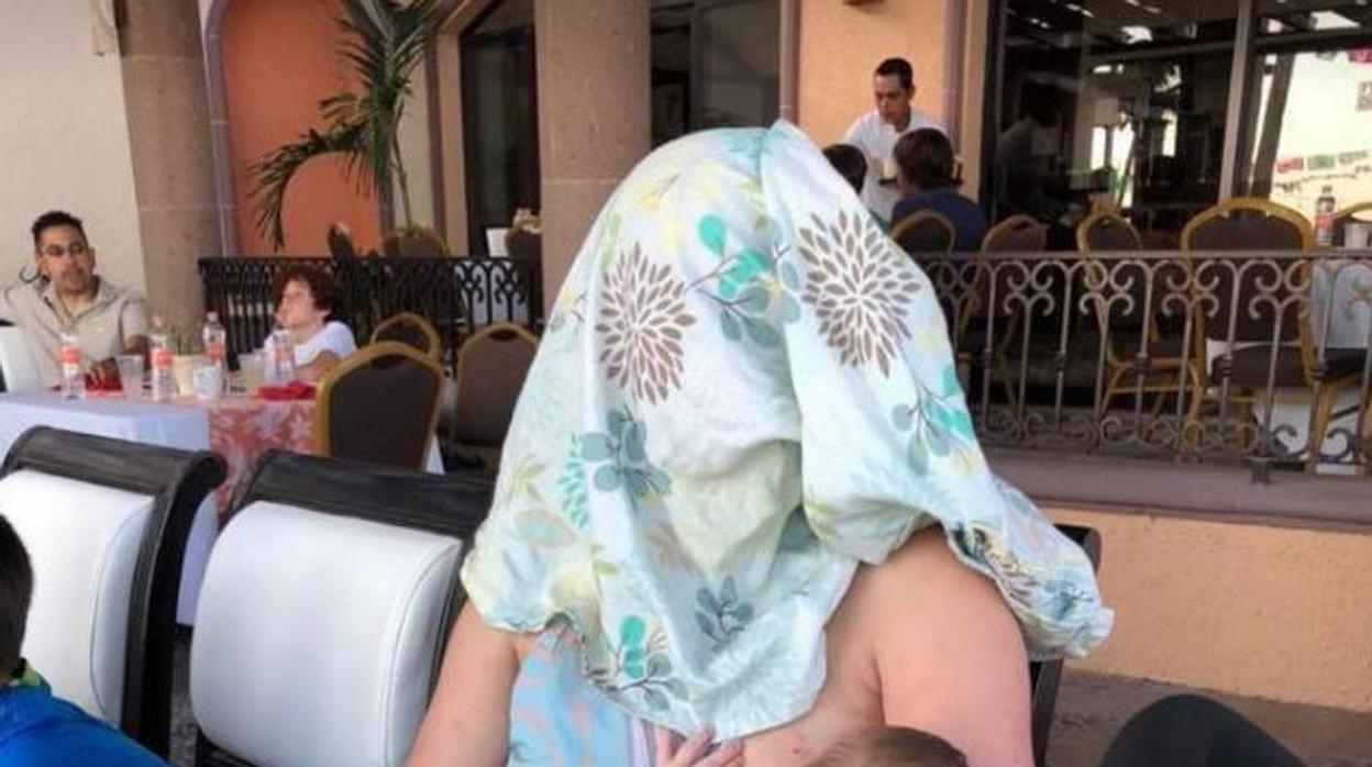 La mujer, con un pañuelo en la cabeza al dar el pecho a su bebé