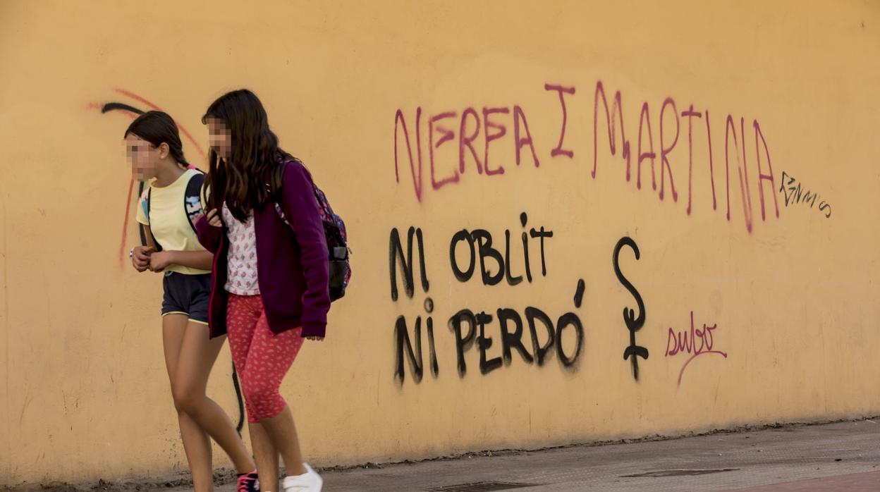 Dos chicas pasan junto a uuna pintada en memoria de las niñas asesinadas por su padre