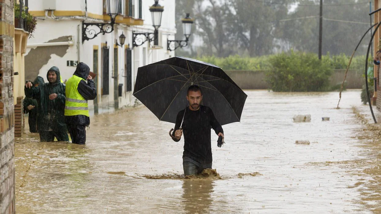 Una persona camina entre las casas inundadas en la barriada Doña Ana de la localidad malagueña de Cártama por las fuertes lluvias en 2016