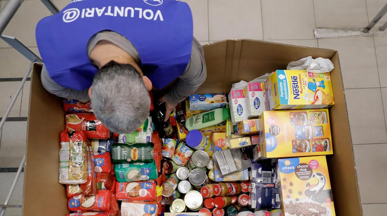 Un voluntario ordena los alimentos en una caja en un supermercado de Valencia