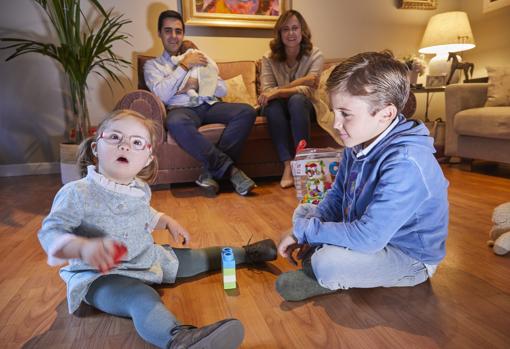 Loreto juega con su hermano Gonzalo mientras sus padres, que sujetan a Mar, los miran