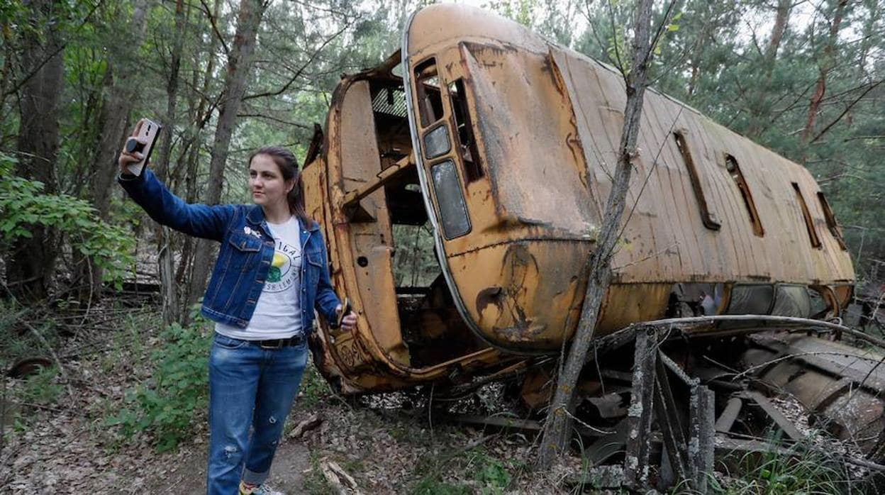Una mujer se fotografía junto a un autobús abandonado durante una visita guiada a Chernóbil