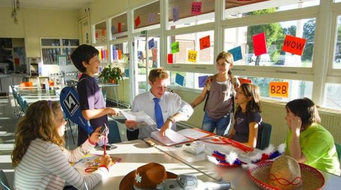 Grupo de alumnos hace los deberes junto a un profesor