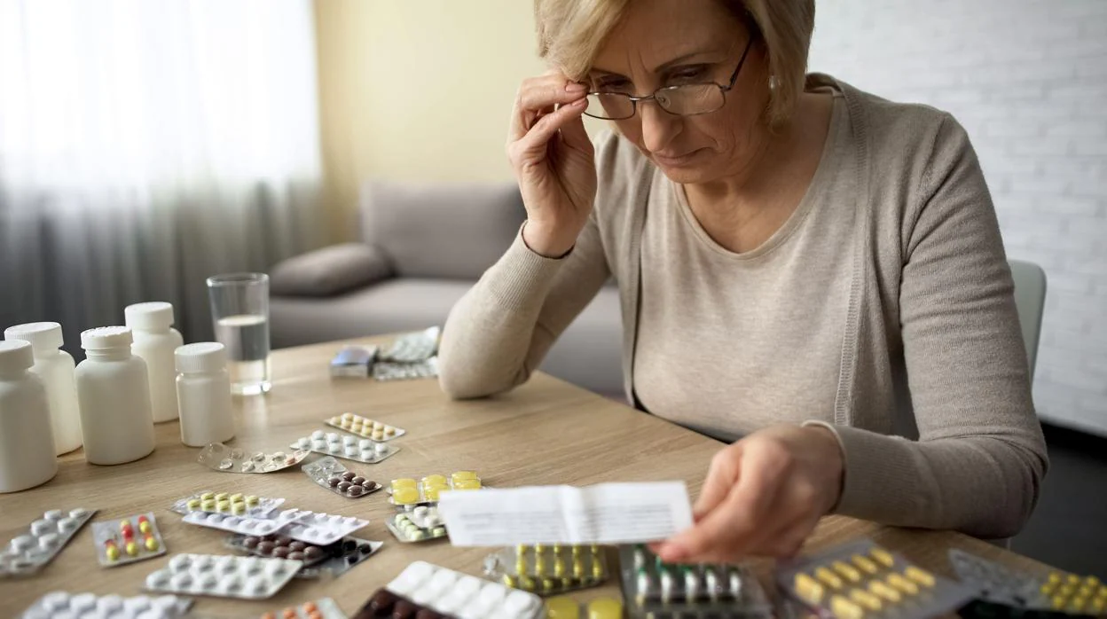 Una mujer consulta el prospecto de los fármacos que le han prescrito